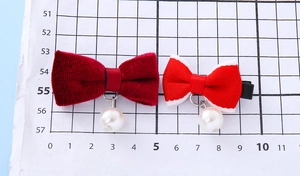 Dettaglio dei fermagli per capelli a fiocco in velluto rosso con eleganti ciondoli a perla