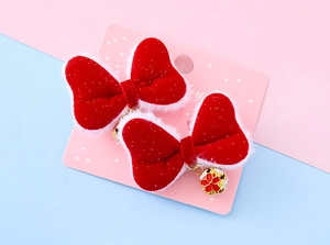 Detail of red velvet bow hair clips with white plush trim and golden bell charms