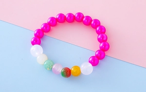 Detailed view of colorful beaded girl's bracelet with bright pink beads and pop-style charms