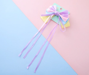 Close-up of multi-color satin bow hair clip with long ribbons and a heart-shaped backing