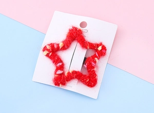 Détail d'une pince à cheveux étoile en tricot rouge avec points colorés