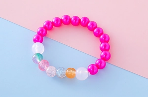 Close-up of girls' bracelet with vibrant pink beads and colorful crackle textured pearls