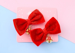 Close-up of red velvet bow hair clips with gold flower bell pendants for kids