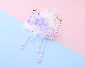 Detail of purple gradient fabric flower hair clips with soft white feathers and long tassels