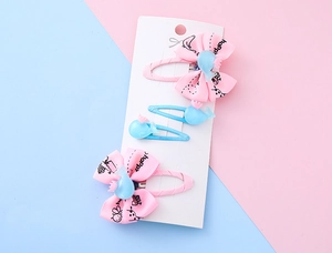 Dettaglio di un set da 4 pezzi con fiocchi rosa e fermagli per balene blu per bambini