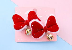 Close-up of velvet red bow hair clips with white faux fur and golden bells for kids