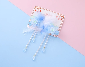 Detail of blue silk flower hair clip with white feathers and pearl tassels on card