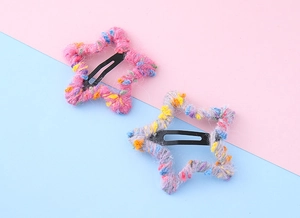 Détail de barrettes étoiles en laine tricotée à la main avec de petits pompons colorés