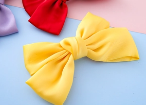 Detail of yellow handmade satin fabric bow hair clip for girls with a smooth glossy texture