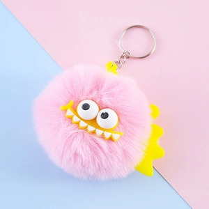 Pink faux rabbit fur monster keychain with funny face on blue and pink background