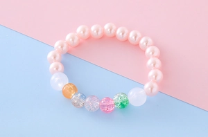 Macro shot of colorful beaded bracelet for girls with pink pearls and cracked texture beads