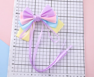 Macro view of multi-layer colorful bow hair clip with long purple ribbons and satin finish