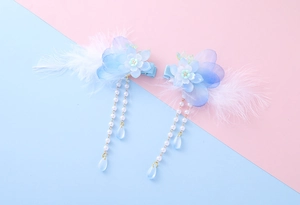 Detailed close-up of blue flower hair clips with long pearl tassels and white feathers