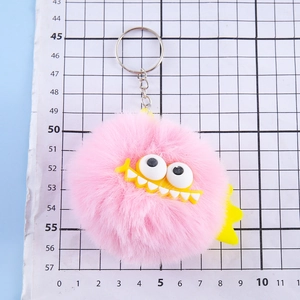 Pink faux rabbit fur monster keychain with big eyes and metal clasp on scale background