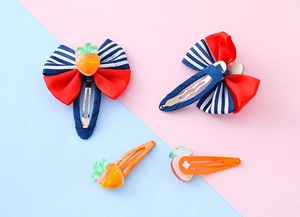 Dettaglio di fermagli per capelli per bambini con fiocchi a righe e carote colorate