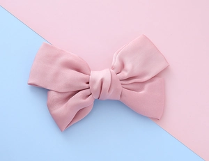 Close-up of pink satin bow hair clip with glossy silk texture for girls