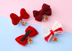 Detail view of four red bow hair clips with cherry blossom bells and metal duckbill clips
