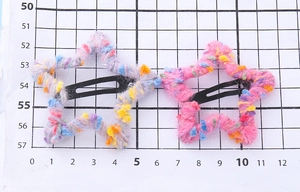 Vue détaillée de deux pinces à cheveux en forme d'étoile en laine arc-en-ciel sur support