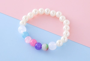 Detail of beaded girl bracelet with milky faux pearls and colorful decorative resin beads