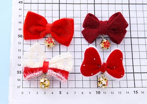 Detailed close-up of red velvet bow hair clips with decorative bell pendants on grid paper