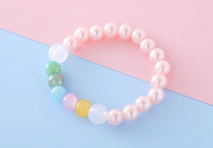 Close-up of pink imitation pearl bracelet with colorful crackle beads on pastel background