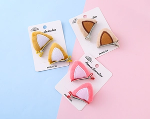 Detalle de pinzas para el pelo con orejas de gato de felpa en rosa, marrón y amarillo