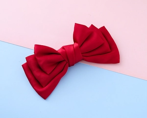 Detailed close-up of a layered red satin ribbon bow hair clip for girls and women