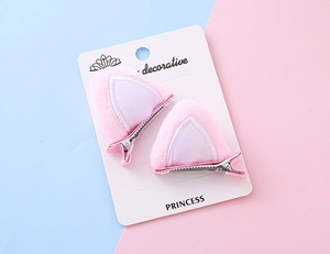 Detalle de pinzas de pelo con orejas de gato de felpa rosa sobre tarjeta decorativa