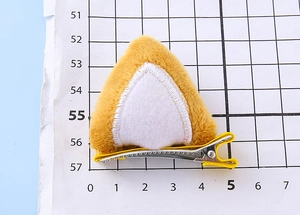 Detalle de pinza para pelo de oreja de gato en peluche amarillo con interior de fieltro blanco
