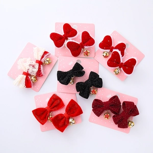 Red bow hair clip set with bells and floral charms for children on a pink card