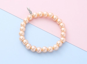 Detail van de champagne parel telefoonarmband met glanzende kralen en zilveren karabijnsluiting