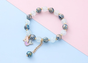 Detail eines Kinderarmbands mit blauen Wirbelperlen und lila Meerjungfrau-Anhänger