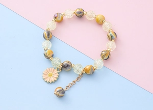 Detail eines Perlenarmbandes für Kinder mit Gänseblümchen-Anhänger und bunten Perlen