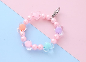 Detail shot of colorful beaded keychain with heart charms and lobster clasp on dual-tone background