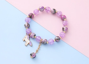 Detailaufnahme des lila Perlenarmbands mit Einhorn-Anhänger und goldenen Akzenten