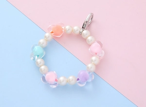 Detail of beaded keychain with white pearls, colorful transparent hearts, and lobster clasp