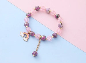 Detail eines rosa und lila Perlenarmbands für Kinder mit buntem Regenbogenanhänger