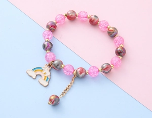 Detailansicht eines rosa Perlenarmbands mit Regenbogen-Einhorn-Anhänger und Goldketten