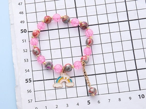 Detailansicht eines rosa Perlenarmbandes mit buntem Regenbogen-Einhorn-Anhänger