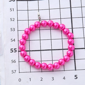 Roze parel polsband voor kinderen met zilveren sluiting op een liniaal achtergrond