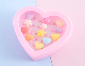 Pink heart-shaped storage box with 12 colorful resin rings in flower and star shapes