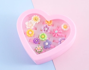 Close-up of colorful resin flower rings for kids in a pink heart-shaped display box