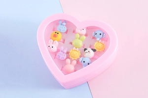 Detail of 12 cartoon resin rings for kids in a pink heart-shaped display gift box