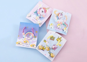 Vista piatta di set gioielli per bambini con ciondoli a unicorno, arcobaleno e corona