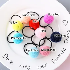 Set of 9 colorful pom-pom elastic hair ties in various candy colors on a ceramic tray