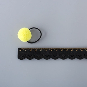 Cute yellow pompom hair tie with black high-elastic rubber band on a grey background
