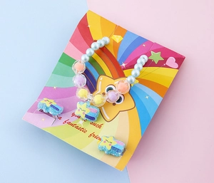 Dettaglio set gioielli bimbi con bracciale di perline e mollette stella su carta arcobaleno