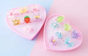 Dettaglio di anelli per bambini in resina glitterata con corone e fiori in scatole
