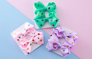 Detailed set of handmade grosgrain ribbon hair clips with colorful metallic heart patterns