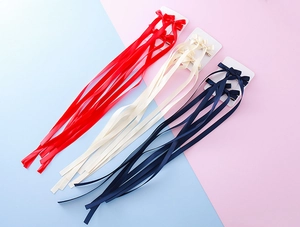 Détail de barrettes à nœuds avec longs rubans en satin rouge, beige et bleu marine chic
